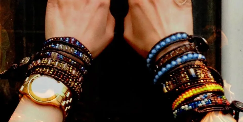 Two raised hands, wrists stacked with colourful wrap bracelets