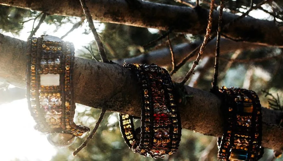 Three beaded cuffs hanging on a pine branch