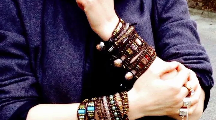 Crossed arms in a wool coat, both wrists stacked with bracelets