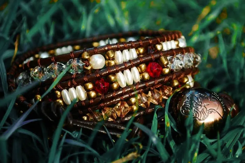 Wrap bracelet with pearls and red crystal lying in the grass