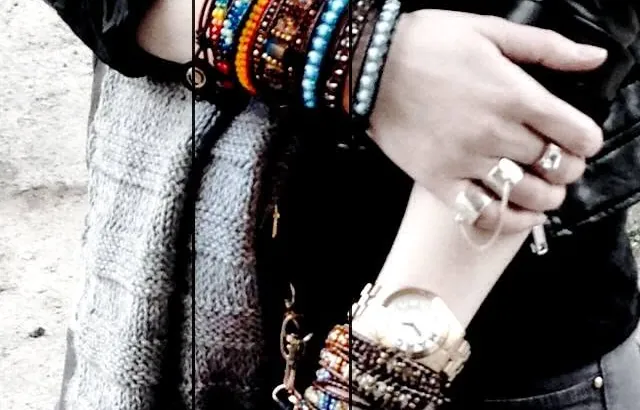 Two wrists stacked with wrap bracelets beside a grey knitted scarf