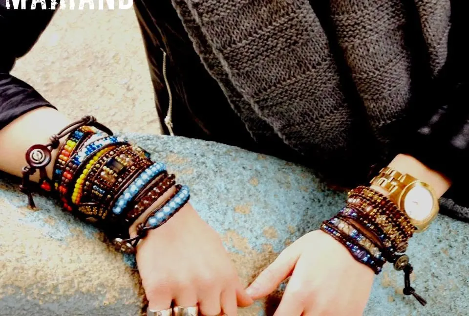 Two arms resting on stone, wearing many wrap bracelets